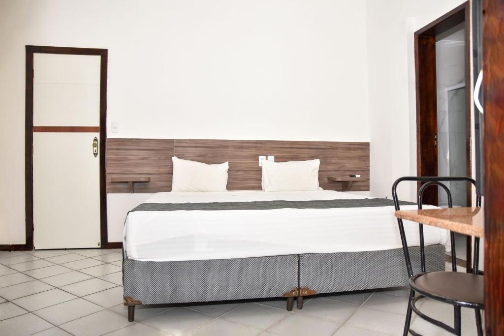 a bedroom with a large bed and a chair at Duna´s guest house in Salvador