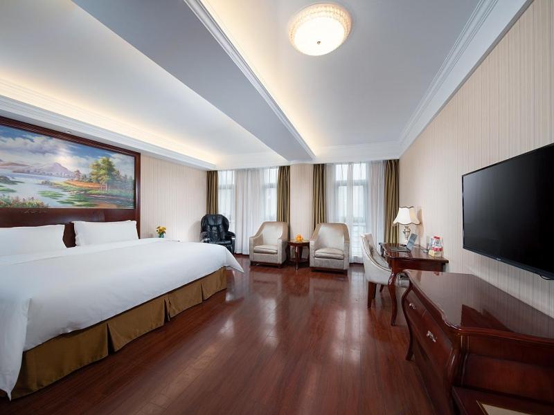 Vienna Hotel Chongqing Chuangyi Park في Shiping: غرفة نوم بسرير كبير وتلفزيون بشاشة مسطحة