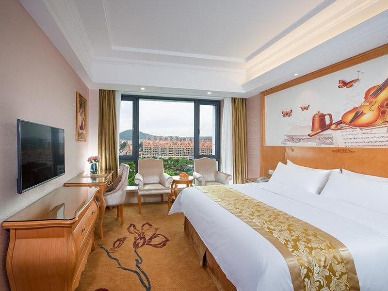 a hotel room with a large bed and a large window at Vienna Hotel Guangdong Zhongshan Nanlang in Zhongshan