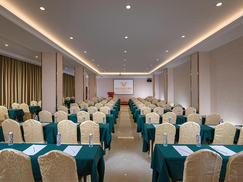 a conference room with tables and chairs and a screen at Vienna Hotel Shenzhen Fuyong Village in Fenghuangwei