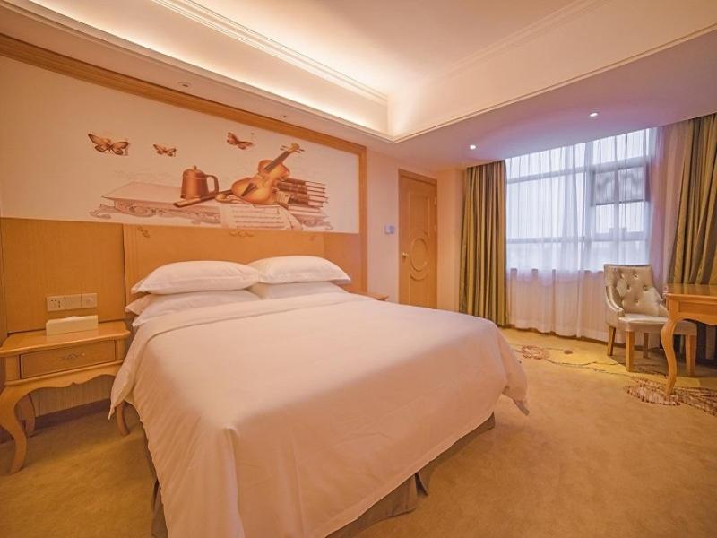 una camera da letto con un grande letto bianco e una finestra di Vienna 3 Best Hotel Luoding Chuangyue Building a Shuangdongjieban