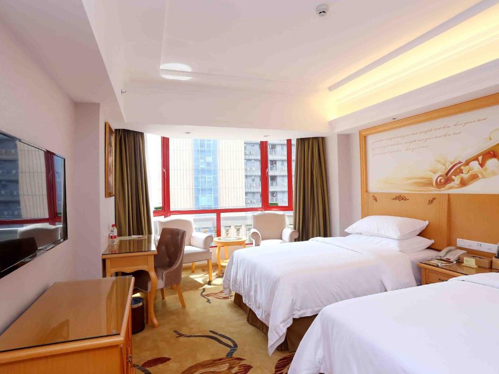 a hotel room with two beds and a television at Vienna Hotel Zhongshan West District in Zhongshan