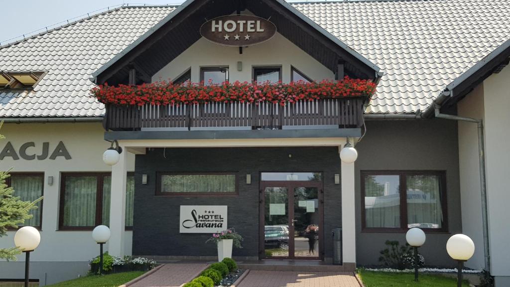 a hotel with a balcony with red flowers on it at Hotel Savana in Kłaj