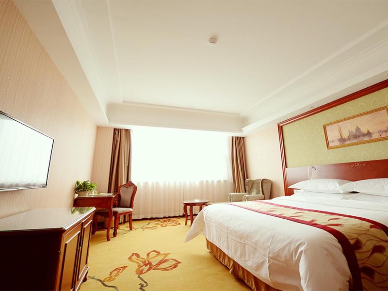 een hotelkamer met een bed en een bureau bij Vienna Hotel Shanghai Jiading New City in Shanghai