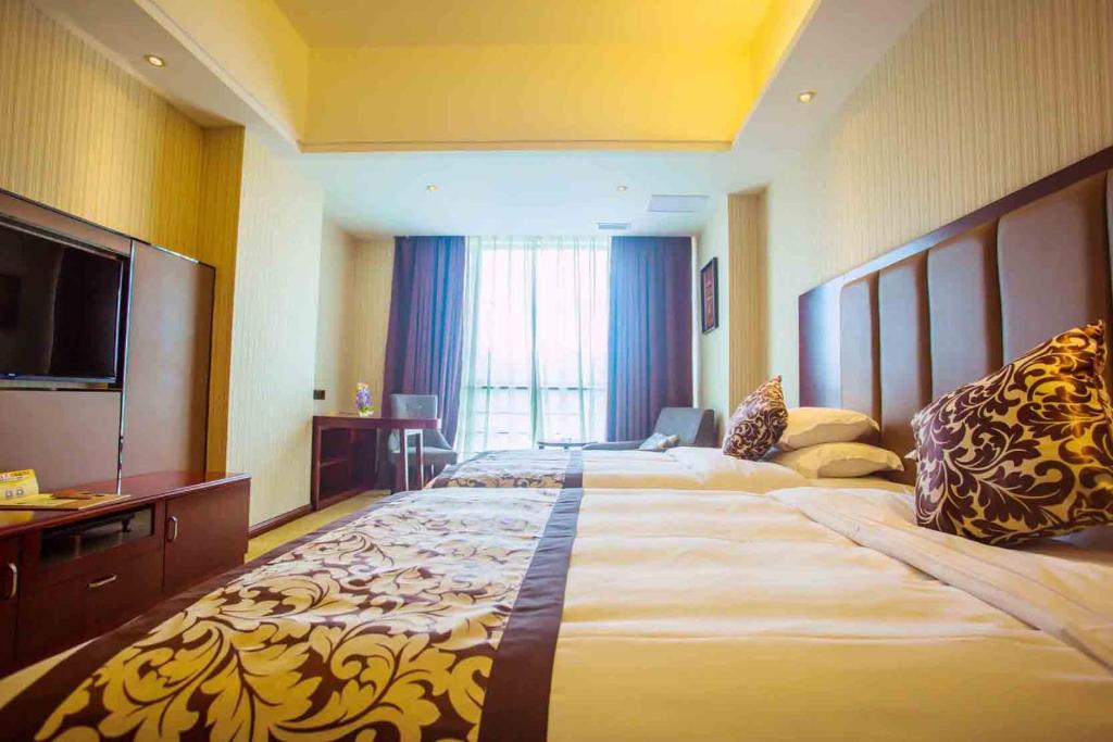 Vienna International Hotel Fuzhou Cangshan Longfu في فوتشو: غرفة فندقية بسريرين وتلفزيون بشاشة مسطحة