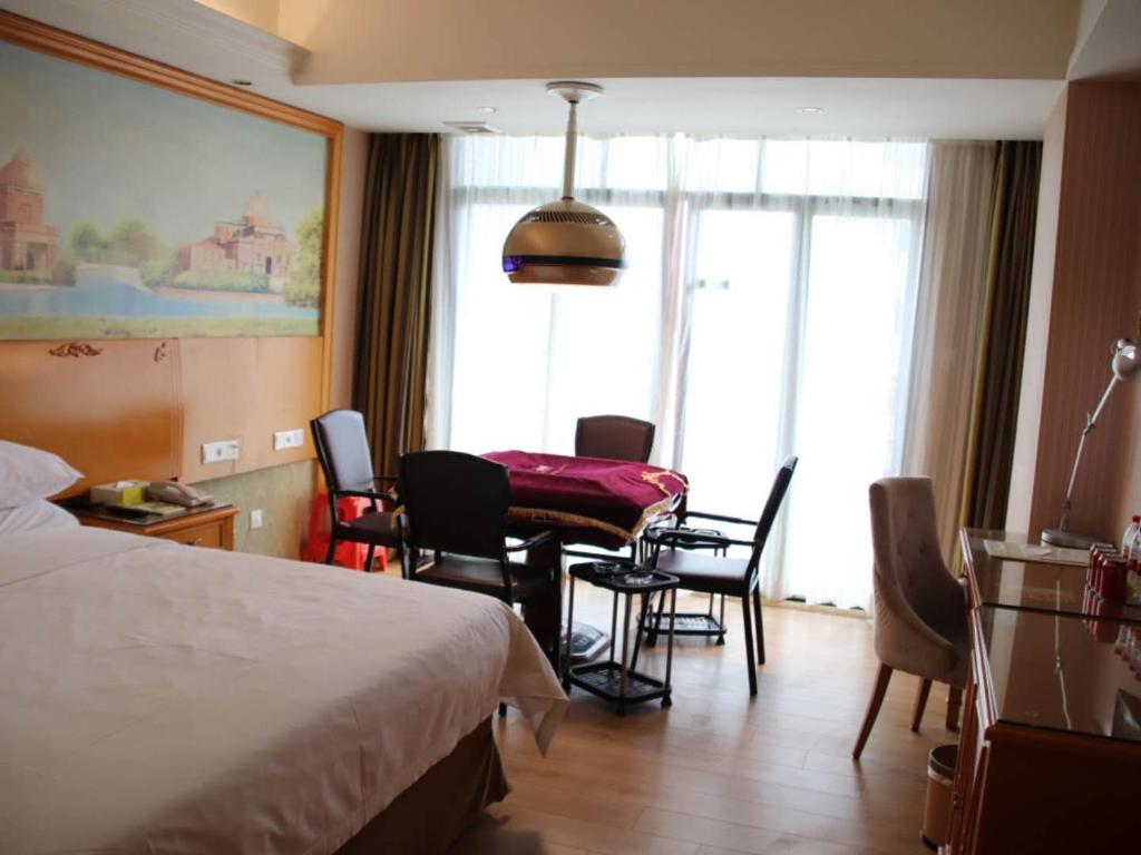 Vienna Hotel Guangdong Huizhou Yuanzhou في Yuanzhou: غرفة فندقية بسرير وطاولة وكراسي