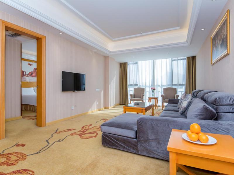 a living room with a blue couch and a tv at Vienna Hotel Hubei Xiangyang Tanxi Road in Xiangyang