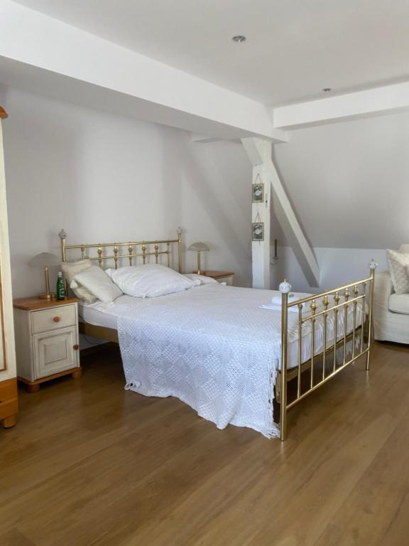 a white bedroom with a bed and a wooden floor at Domek pod lasem in Kołczygłowy