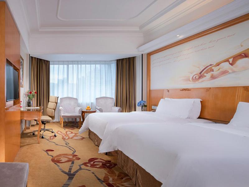 a hotel room with a large bed and a desk at Vienna International Hotel Zhuhai Golden Phoenix in Zhuhai
