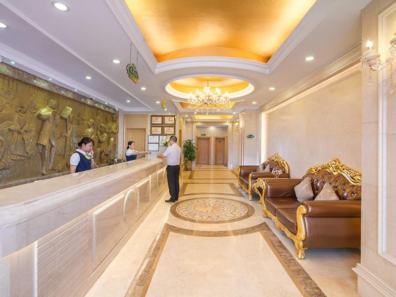 a hotel lobby with people standing at a bar at Vienna 3 Best Hotel Exhibition Center Chigang Road in Guangzhou