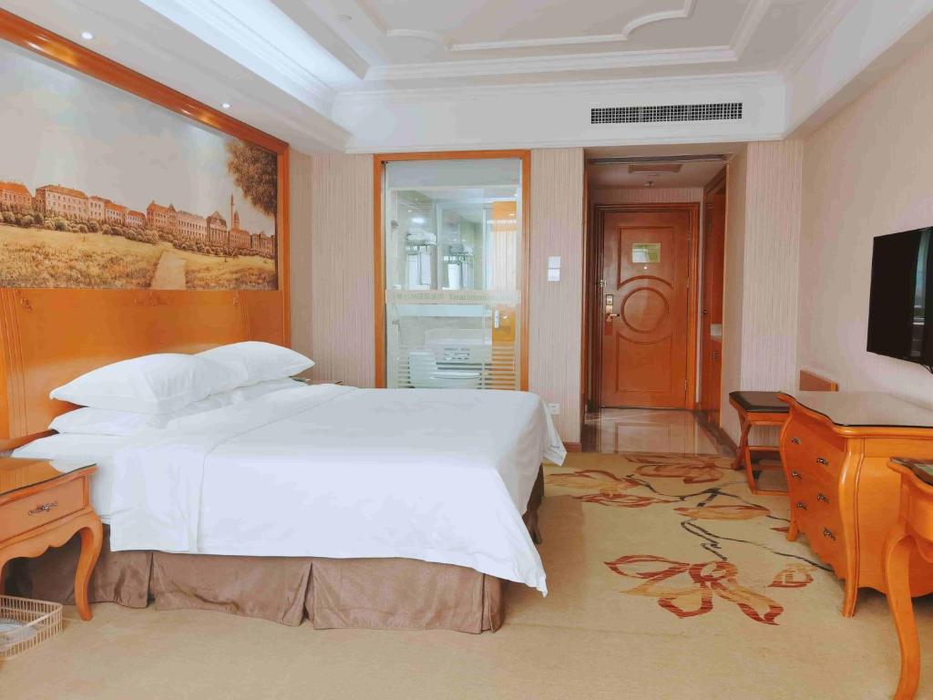 Guigang的住宿－維也納國際酒店廣西貴港荷城路店，卧室配有白色的床和平面电视。