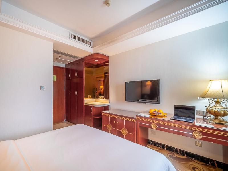 a bedroom with a bed and a desk with a television at Vienna Hotel Foshan Chancheng Zumiao Branch in Foshan