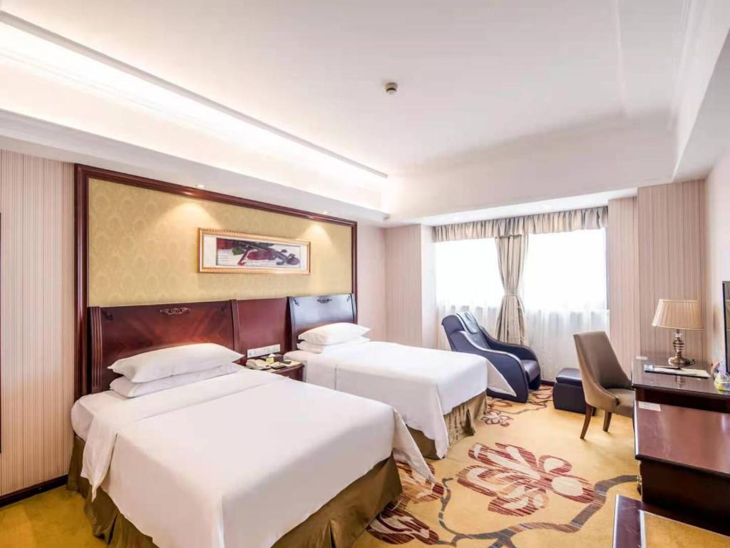 Cette chambre comprend deux lits et un bureau. dans l'établissement Vienna International Hotel Shanghai Pudong Xiupu Road, à Shanghai