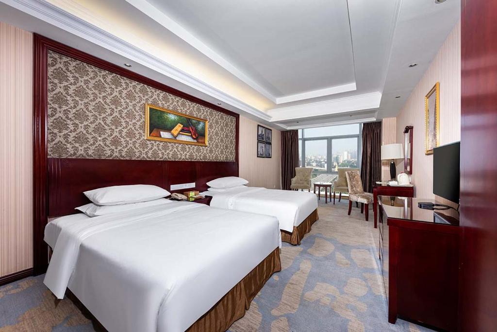 ein Hotelzimmer mit 2 Betten und einem Schreibtisch in der Unterkunft Vienna Hotel Xinyu Kaiguang in Xinyu