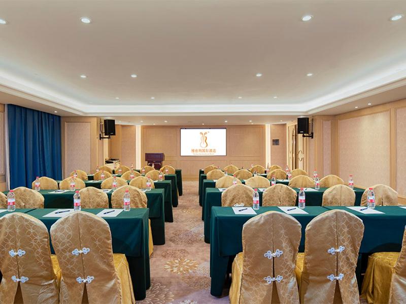 a conference room with tables and chairs and a screen at Vienna International Hotel (Jiaxing Nanhu Hotel) in Jiaxing