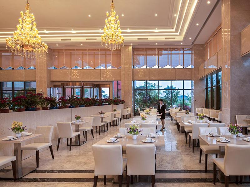 a dining room with tables and chairs and a person walking in the background at Vienna International Hotel (Guangdong Yunfu Emerging New City Plaza Store) in Dongkou