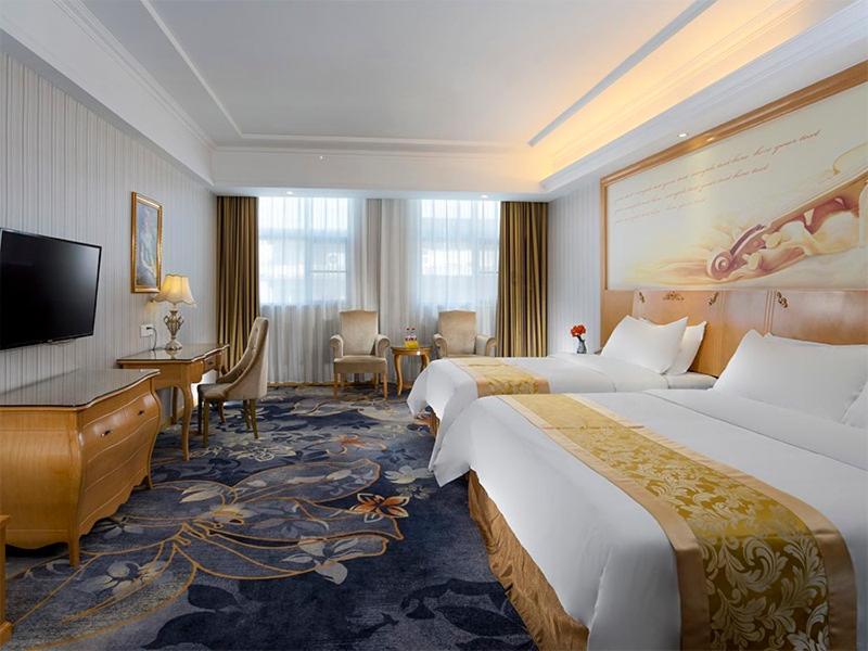 a hotel room with two beds and a desk at Vienna Hotel Meizhou Jiangnan in Meizhou