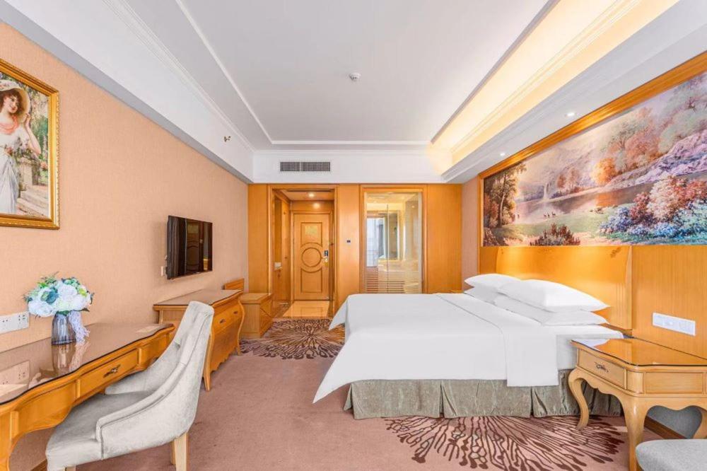 a hotel room with a bed and a painting on the wall at Vienna Hotel Foshan Airport in Foshan