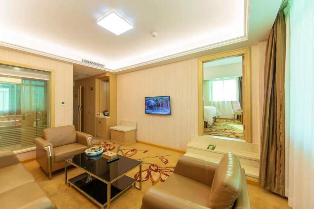 uma sala de estar com um sofá e uma mesa em Vienna Hotel Huizhou Railway Station em Huizhou