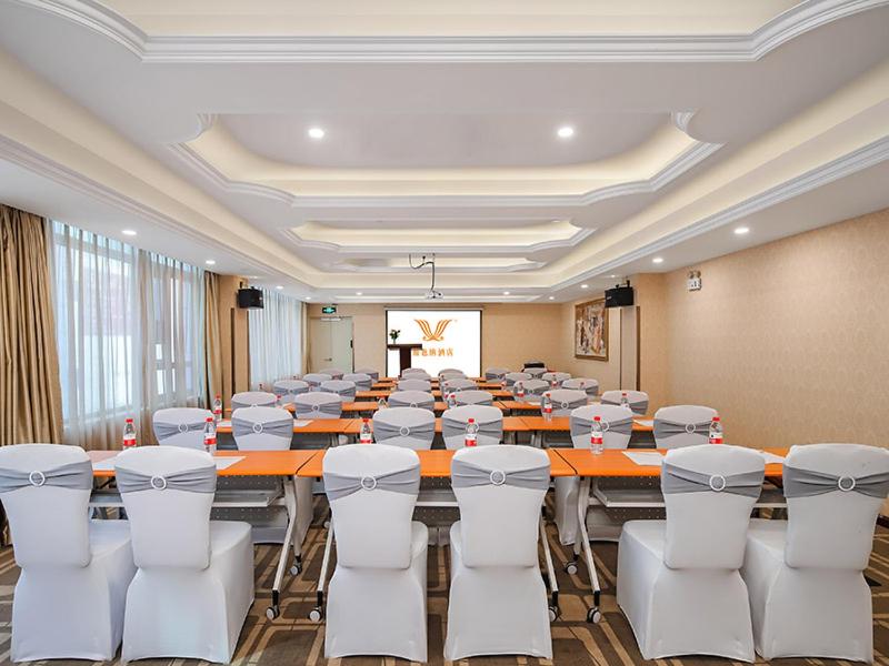 Vienna Hotel Jiangsu Shuyang Middle Renmin Road في Shuyang: قاعة اجتماعات كبيرة مع طاولة وكراسي كبيرة