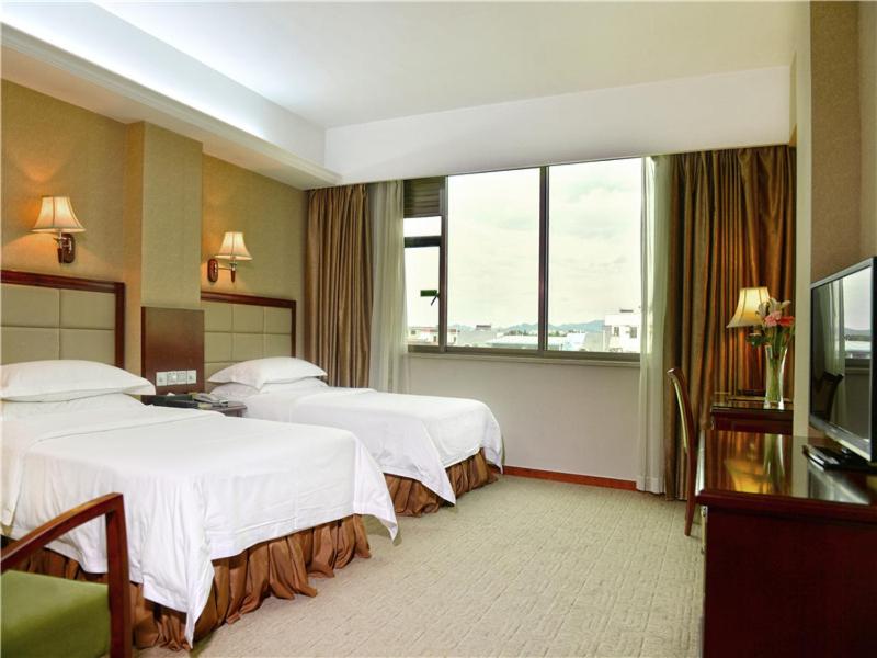 a hotel room with two beds and a television at Vienna Hotel Meizhou railway station in Meizhou