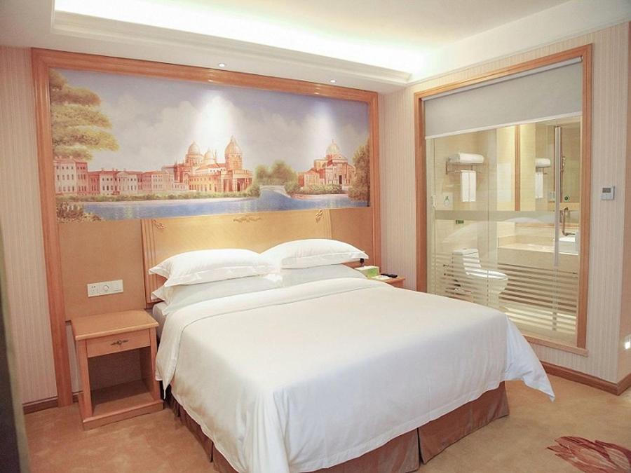 um quarto com uma cama grande e uma pintura na parede em Vienna Hotel Qingyuan Yingde Guangming Road em Yingde