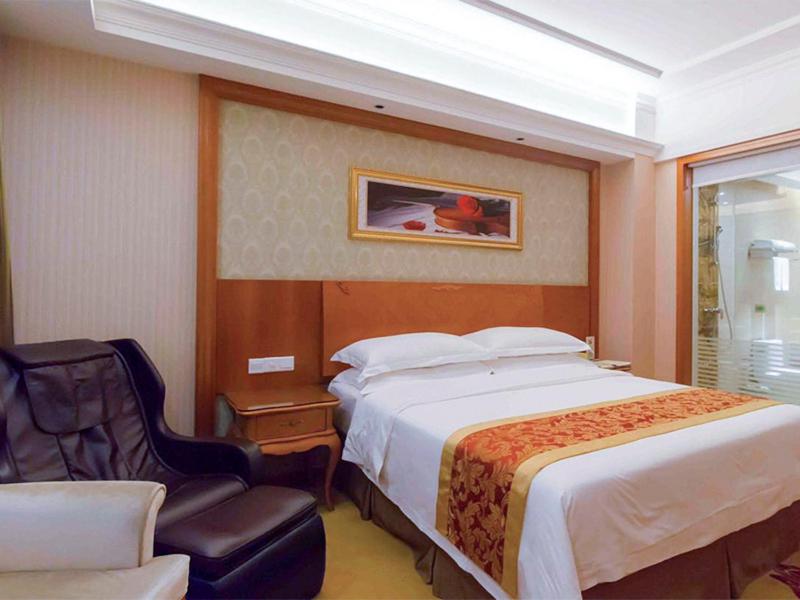 a bedroom with a large bed and a chair at Vienna Hotel Chaoyang High-Speed Train Station in Shantou