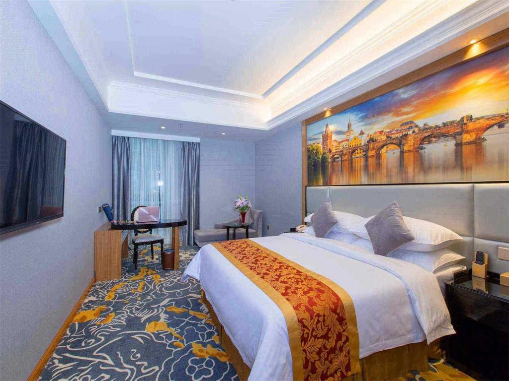 een slaapkamer met een groot bed en een groot schilderij aan de muur bij Vienna Hotel Dongguan East Bus Station in Dongguan