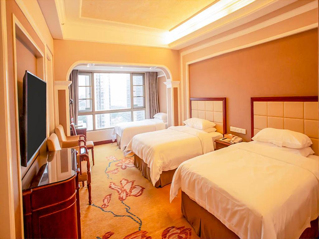 a hotel room with two beds and a flat screen tv at Vienna Hotel Shenzhen Songgang Liye Road in Bao'an