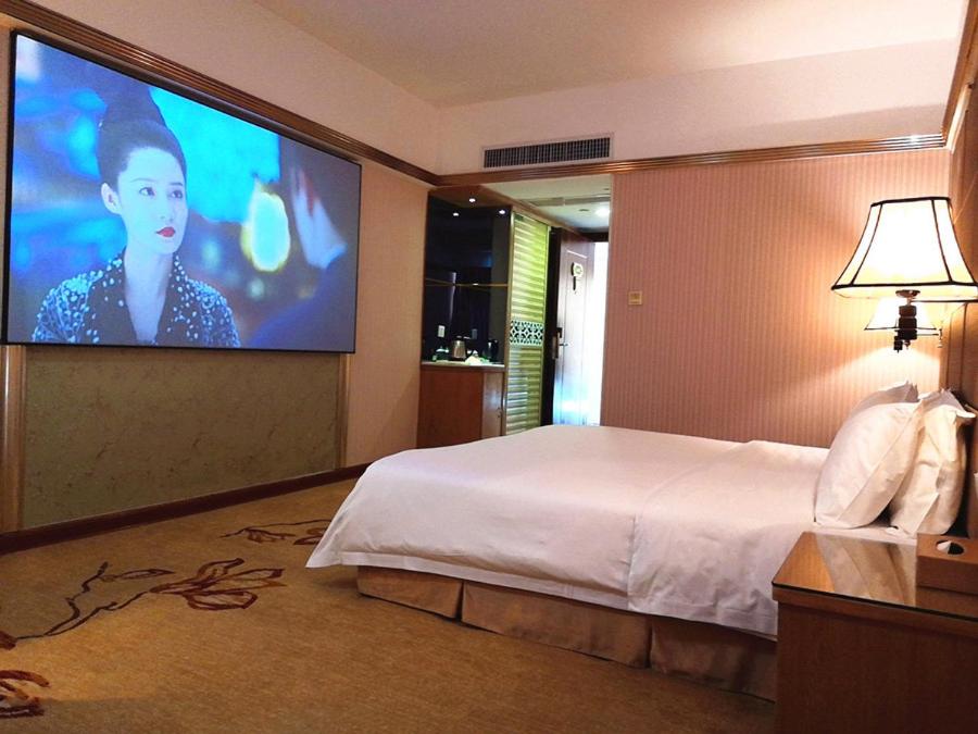a hotel room with a bed and a large screen at Vienna Hotel Zhanjiang Coast Avenue in Zhanjiang