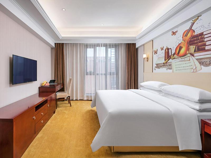 Cette chambre comprend un grand lit et une télévision. dans l'établissement Vienna Hotel Hangzhou Yuhang Linping, à Yuhang