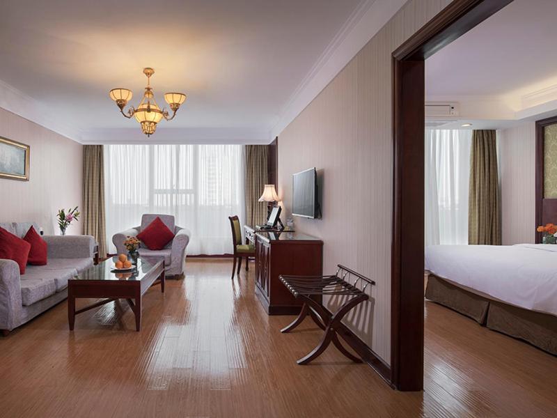 Habitación de hotel con cama y sala de estar. en Vienna International Hotel Taicang Nanyang Plaza, en Taicang