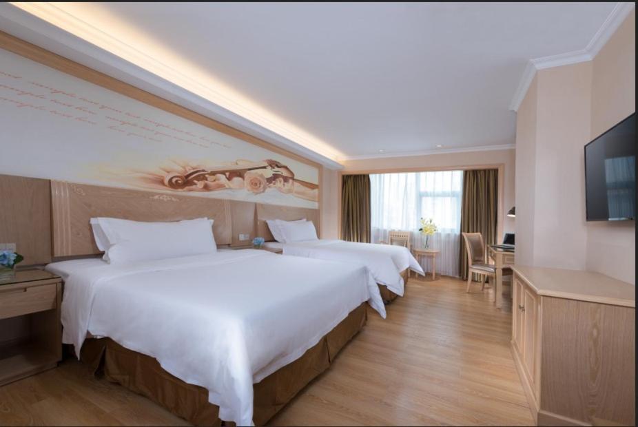 a hotel room with two beds and a television at Vienna Hotel Shenzhen Haiwan in Shenzhen