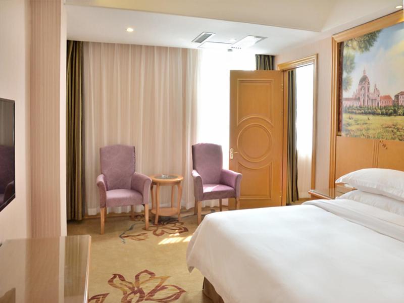 a hotel room with a bed and two chairs at Vienna Hotel Anhui Mingzhu Square in Ershilipu