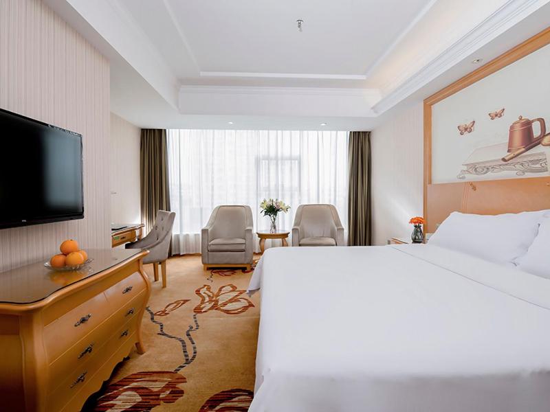 Habitación de hotel con cama y TV de pantalla plana. en Vienna Hotel Jiujiang Railway Station, en Jiujiang