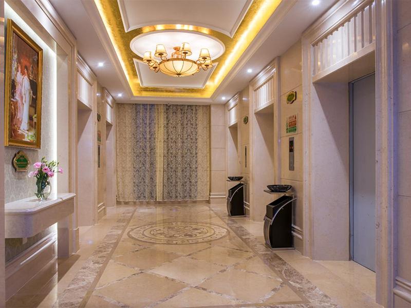 un couloir avec un plafond orné d'un lustre et un couloir avec un couloir dans l'établissement Vienna International Hotel Shenzhen Qianhai, à Shenzhen