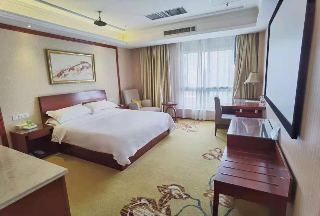 a hotel room with a bed and a flat screen tv at Vienna Hotel Nantong Tongzhou Bus Station in Tongzhou