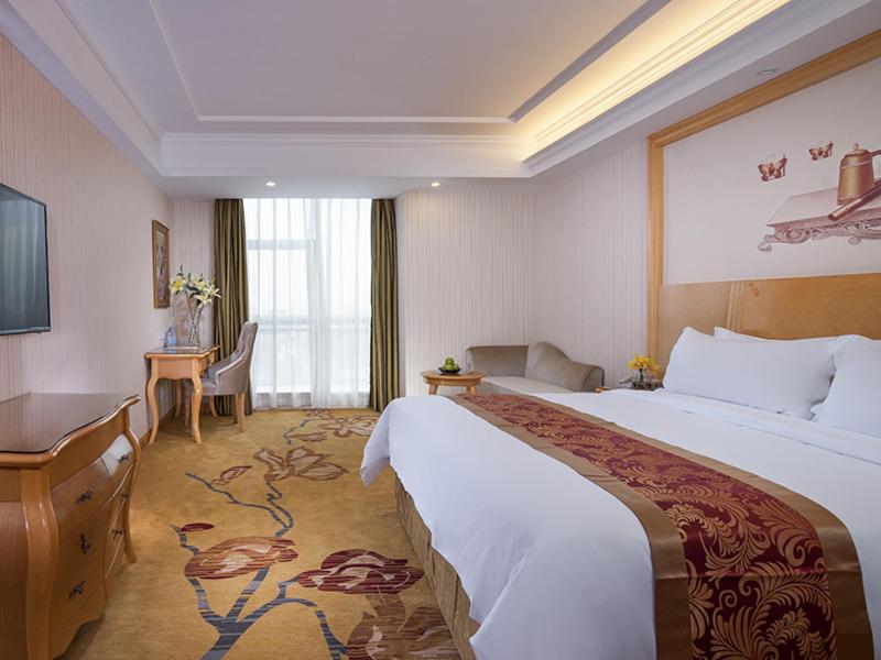 Habitación de hotel con cama grande y escritorio. en Vienna Hotel Dongguan Chengcaiyuan International Plaza, en Dongguan