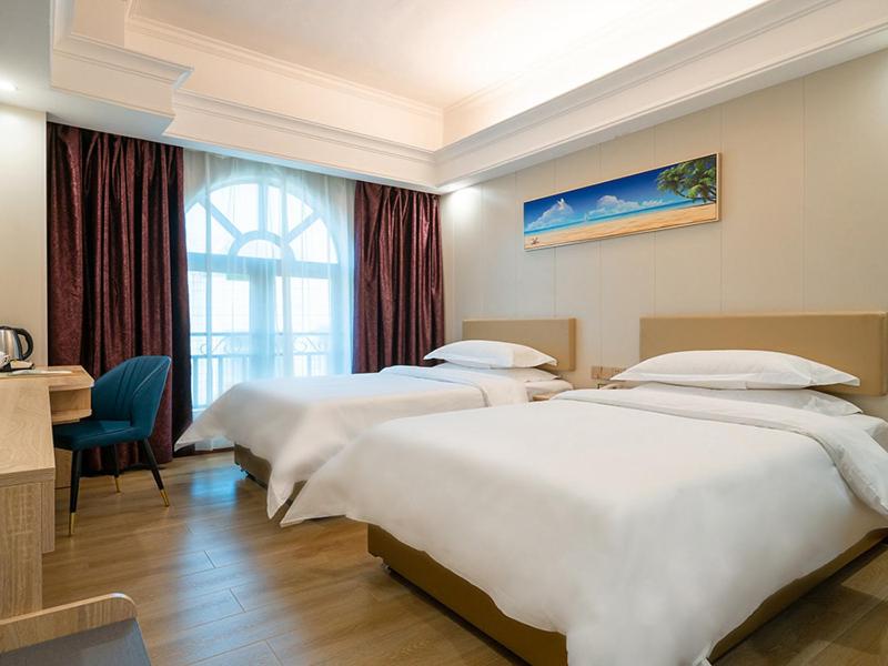a hotel room with three beds and a desk at Vienna Hotel Zhuhai Xiangzhou Bus Station in Zhuhai