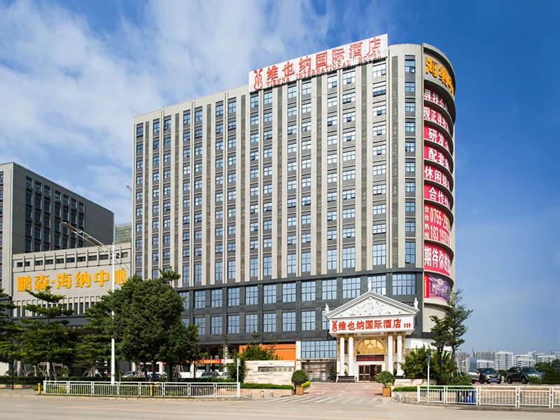 a large white building with red signs on it at Vienna Hotel Shenzhen Guangming Guangqiao Road Tianliao in Shenzhen
