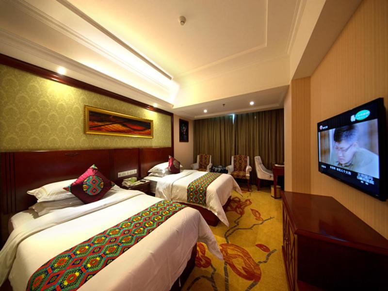 a hotel room with two beds and a flat screen tv at Vienna Hotel Zhangjiajie North Railway Station in Zhangjiajie