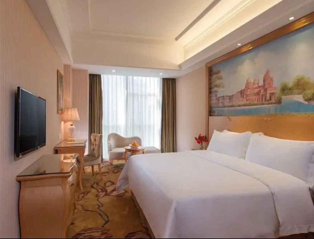 a hotel room with a large bed and a television at Vienna Hotel Shenzhen Baoneng City Plaza in Longgang