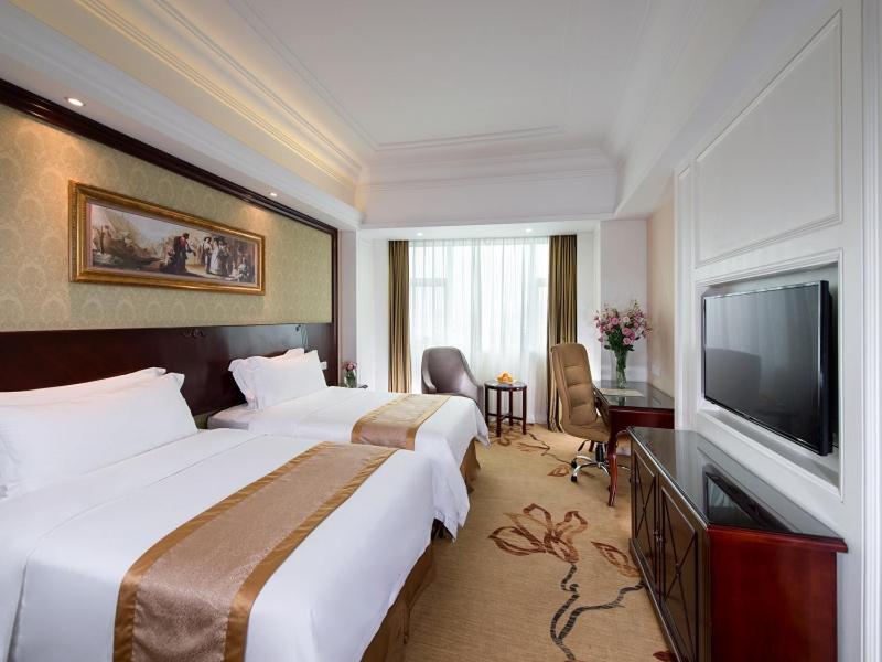 a hotel room with two beds and a flat screen tv at Vienna International Hotel Zhongshan Shiqi Kanghua Road in Zhongshan