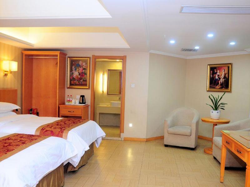 Pokój hotelowy z 2 łóżkami i krzesłem w obiekcie Vienna 3 Best Hotel Hubei Jingmen Huyaguan Avenue Changfa w mieście Jingmen