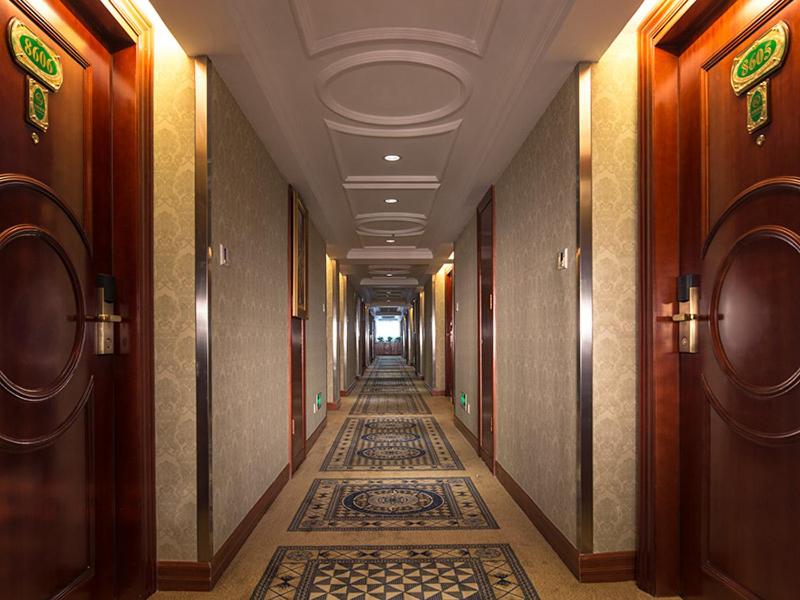 a hallway in a hotel with a tile floor at Vienna Hotel Shenzhen Futian Bagua Road in Shenzhen