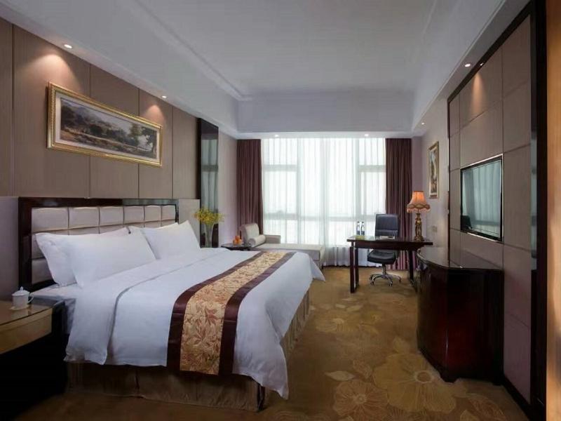 a bedroom with a large bed and a television at Vienna International Hotel Guangdong Zhongshanbei Station in Zhongshan