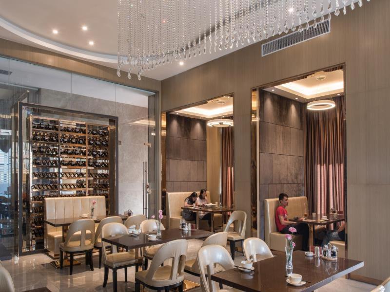 un restaurante con mesas, sillas y botellas de vino en Vienna Classic Hotel Dongguan Changan Xiandai, en Dongguan