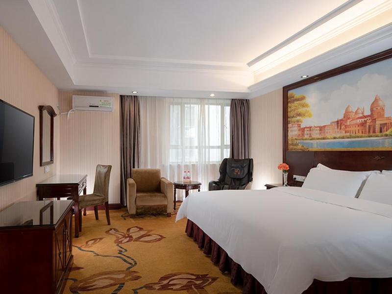 東莞的住宿－維也納酒店東莞長安振安中路店，酒店客房设有一张大床和一张书桌。