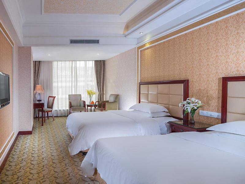 una camera d'albergo con due letti e un tavolo con sedie di Vienna Hotel Songgang Yanchuan Road a Bao'an