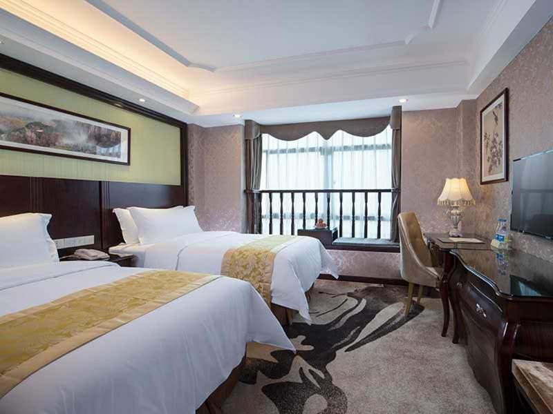 a hotel room with two beds and a television at Vienna 3 Best Hotel Meizhou Mei County People Square in Meizhou